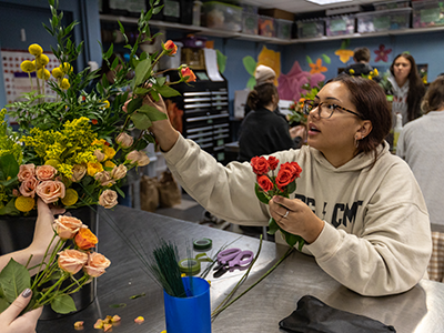 Student working with flower arrangement.