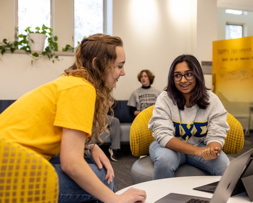 Students talking to each other and looking at computer.