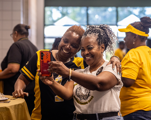 Two women taking photo at Homecoming Tailgate.